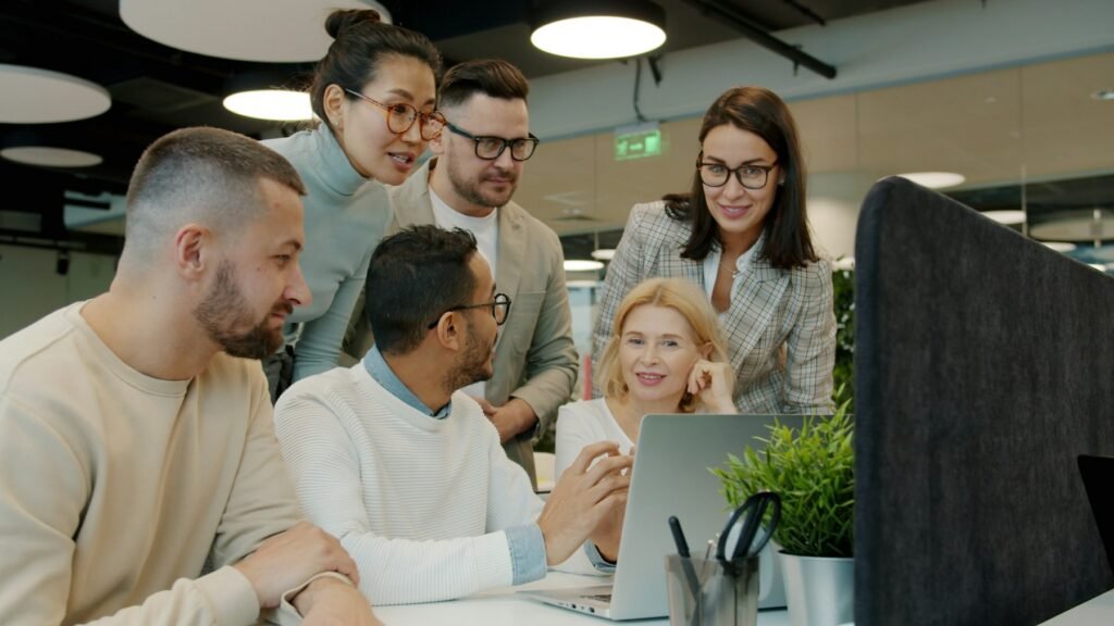 A diverse business technology team collaborating around a laptop